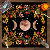 A dark mat featuring a celestial design with a full moon, crescent moons, and floral elements for tarot readings.
