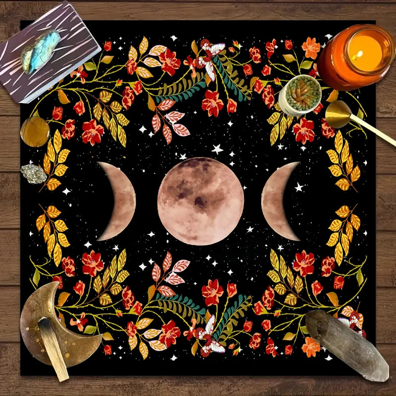 A dark mat featuring a celestial design with a full moon, crescent moons, and floral elements for tarot readings.