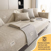 A beige textured sofa cushion with a matching throw blanket and decorative pillows.