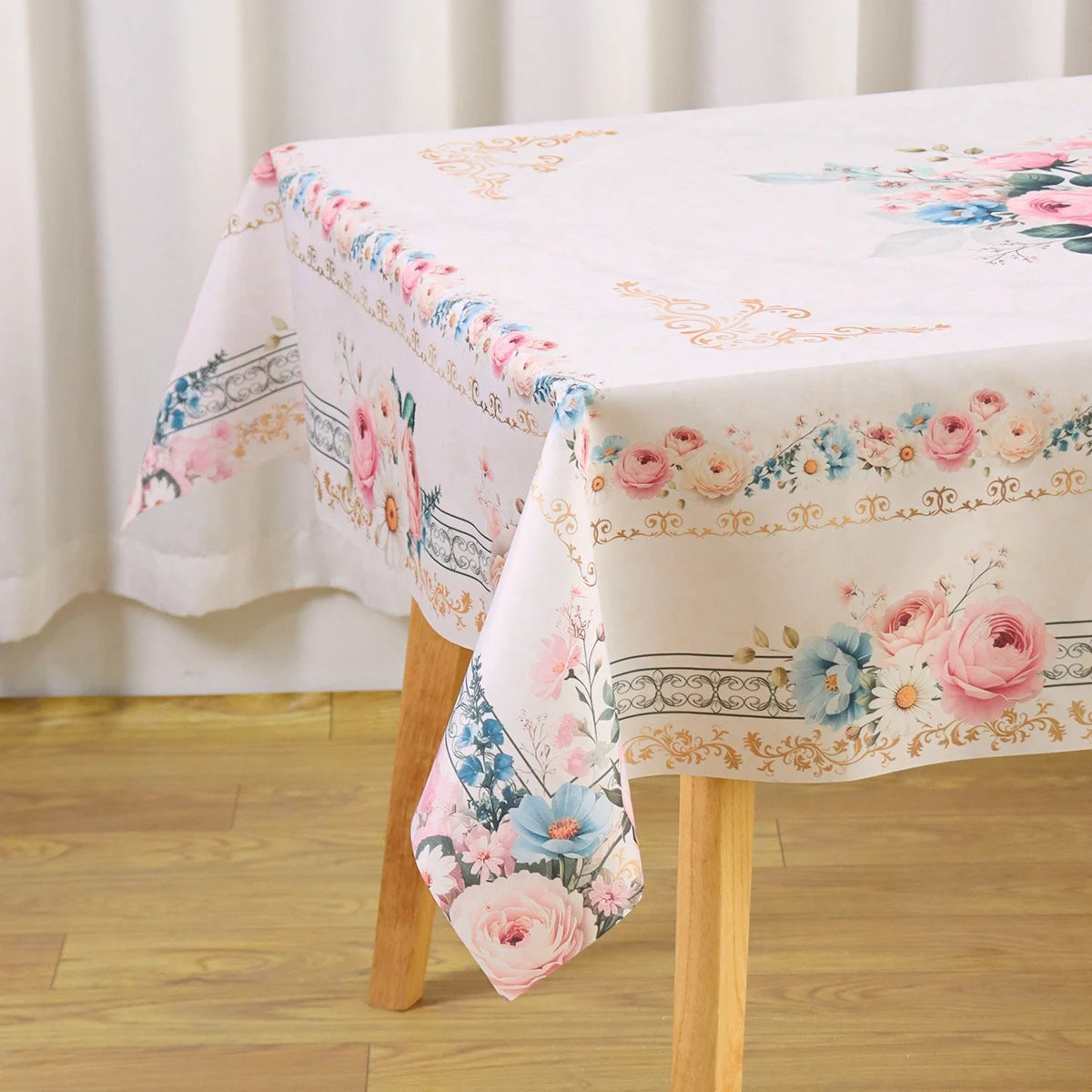 A white tablecloth with a pink and blue floral pattern is displayed on a wooden table.