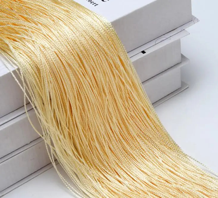 A bundle of golden thread curtain tie-back material is displayed next to a white box.
