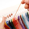 Hands holding colorful embroidery threads and needles for a fish cross stitch kit DIY hobby set