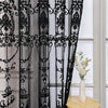 Black sheer curtain featuring intricate lace embroidery with pearl accents hanging in a window.