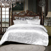 A luxurious white satin duvet cover set displayed on a bed with an ornate wooden headboard and antique lighting.