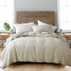 A bed dressed with a beige luxury French linen duvet cover and white pillows against a wooden headboard.