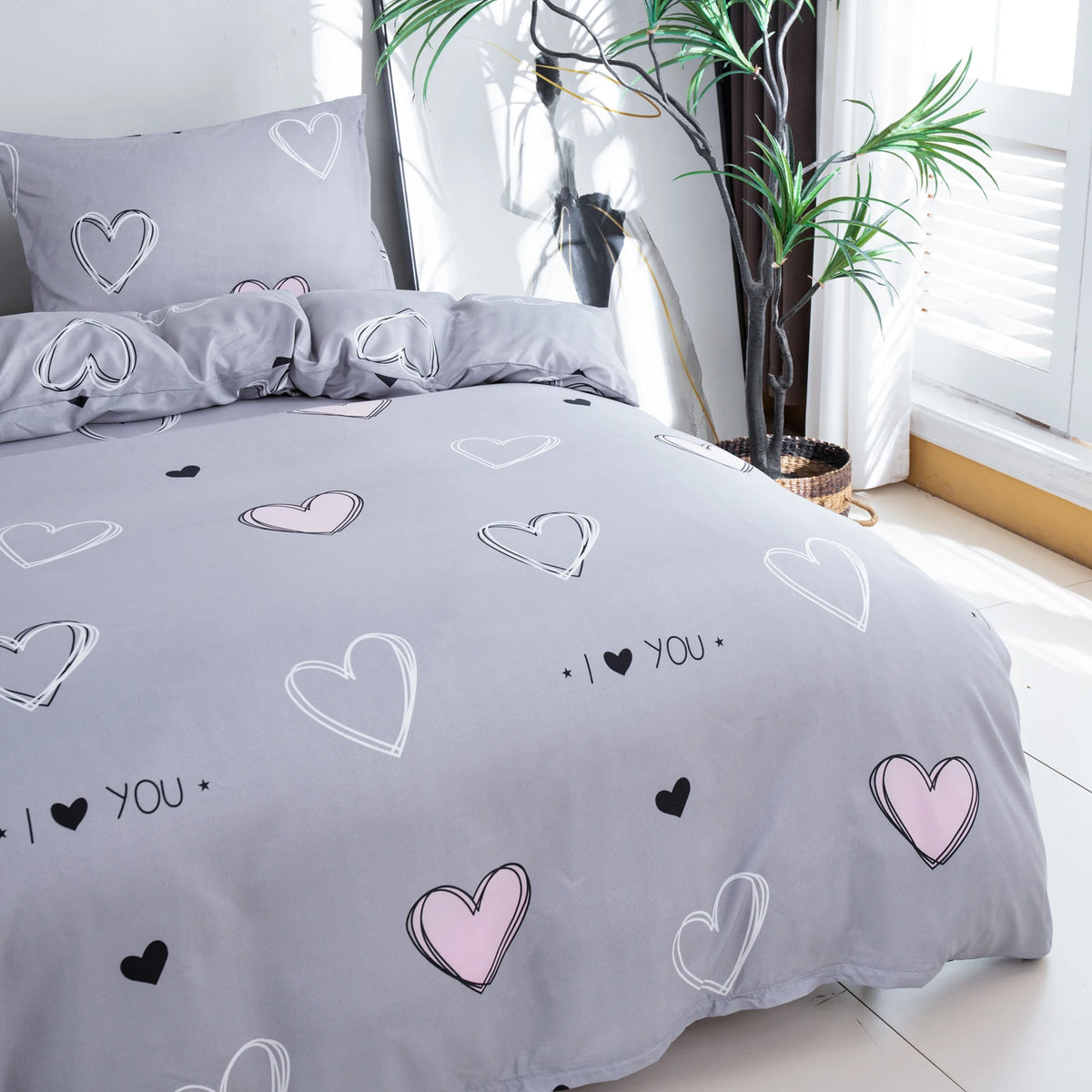 Gray bedding set featuring a pink heart print with various heart shapes on the duvet cover and pillowcases.