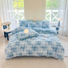 A fluffy blue and white faux fur duvet cover with matching pillows on a bed in a bright room.