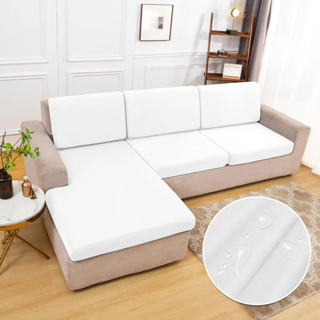 A beige sofa is covered with white waterproof cushion protector covers on a wooden floor.