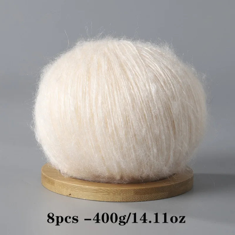 A ball of white mohair yarn resting on a wooden base.