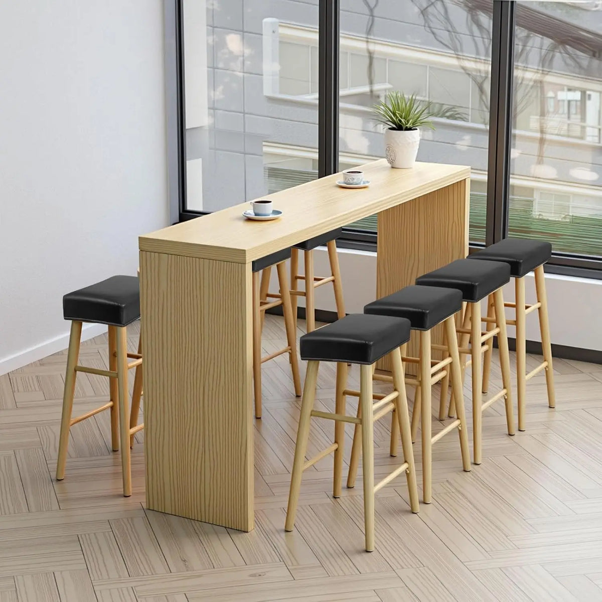 A light wood bar table with matching wooden stools and a potted plant in a modern room.