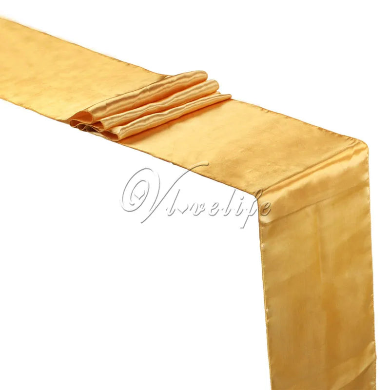 A golden satin table runner draped with a folded fabric on a white background.