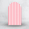 A vertical arch backdrop cover with vertical pink and white stripes against a gray concrete wall.