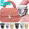 A set of five silver and gold metal bag lock clasps for handbags and totes shown next to a pink crocheted bag.