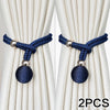 Two navy blue fabric tiebacks with silver accents shown against a cream curtain.