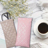 Pink and beige suede-like squeeze-top PU leather eyeglass case with a cleaning cloth next to a cup of coffee