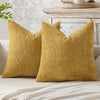 A mustard yellow chenille pillow cover with a textured weave resting on a light-colored sofa.