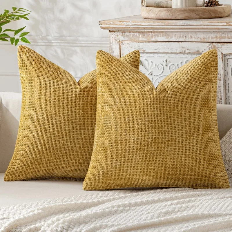 A mustard yellow chenille pillow cover with a textured weave resting on a light-colored sofa.