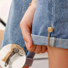 Close-up of a hand wearing gold magnetic chain buckles on denim clothing