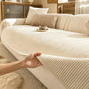 A hand touches the ribbed beige slipcover of a striped chenille sofa, showing its texture and drape.