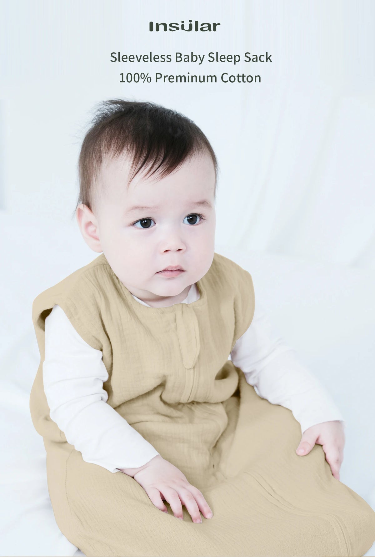 A baby wearing a beige sleeveless sleep sack made of 100% premium cotton.