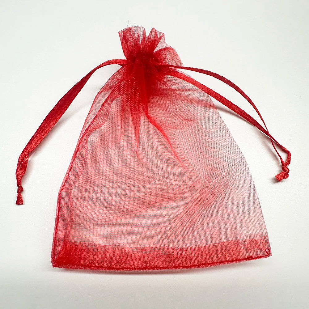 A clear red organza gift bag tied with a ribbon, used for bulk jewelry and candy storage.