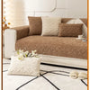 A brown plush sofa cushion cover with cream accent pillows and a white textured rug.