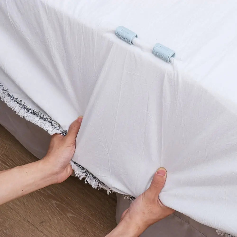 A hand is adjusting a white sheet with light blue invisible clips on a bed covering.