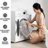 A woman is sitting next to a white washing machine, holding a gray throw blanket, demonstrating its features.