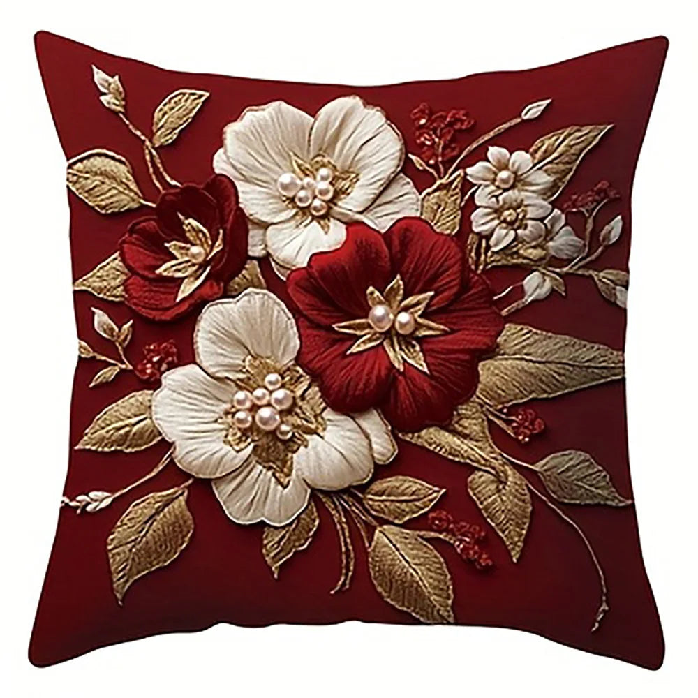 A deep red pillow cover featuring embroidered white and maroon floral designs on a dark background.