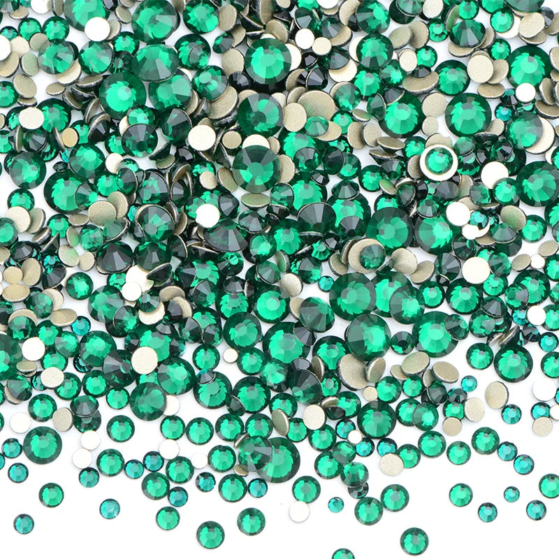 A pile of clear green and gold glass rhinestones for DIY crafts.