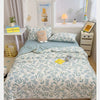 A light blue and white patterned quilt with floral embroidery is displayed on a bed, surrounded by decorative items.