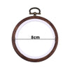 Round wooden embroidery hoop with a brass hook and white fabric inside