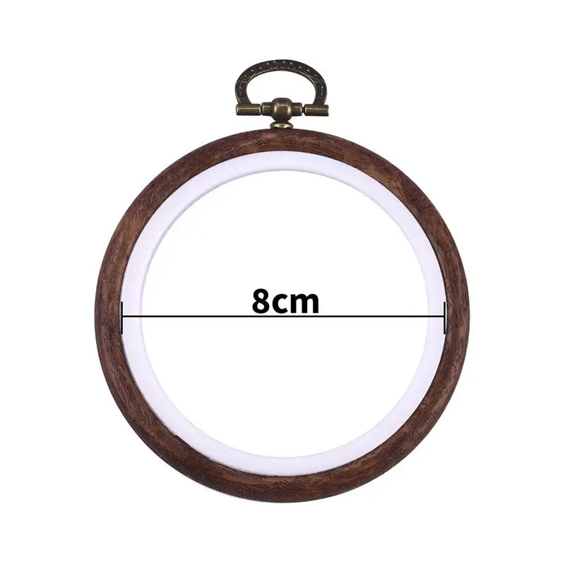 Round wooden embroidery hoop with a brass hook and white fabric inside