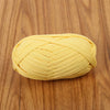 A ball of bright yellow flat thread yarn for crafting and sewing lying on a wooden surface.