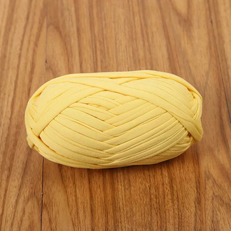 A ball of bright yellow flat thread yarn for crafting and sewing lying on a wooden surface.