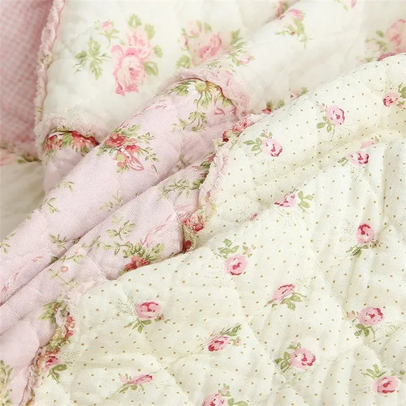Close-up of a pink and white patchwork floral plaid cotton quilt fabric.