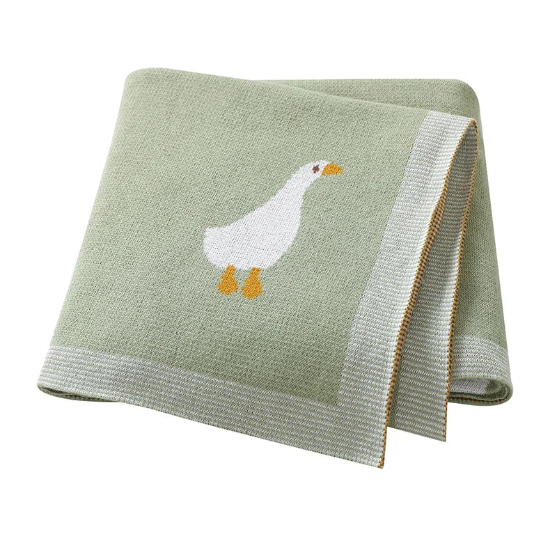 A light green cotton blanket with a white duck illustration and a ribbed edge.
