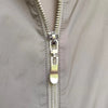 Close-up of a silver metal zipper pull on a gray fabric garment.