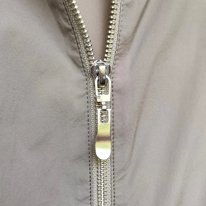 Close-up of a silver metal zipper pull on a gray fabric garment.