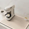 A white Mieg coffee grinder sits on a beige kitchen drain mat on a white countertop.