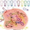 A pile of colorful gourd-shaped locking safety pins for knitting and sewing laid out on a pink knitted background.