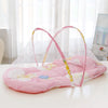 A portable baby crib net with soft pink padding and a clear mesh cover is displayed on a white surface.