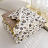 A stack of white and brown patterned Summer Gauze Cotton Quilt folded on a light surface.