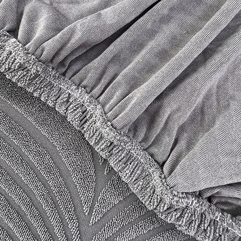 Close-up of a gray jacquard stretch sofa cover with gathered fabric texture.