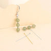A stainless steel ball head pin with a silver hook and three light green beads.