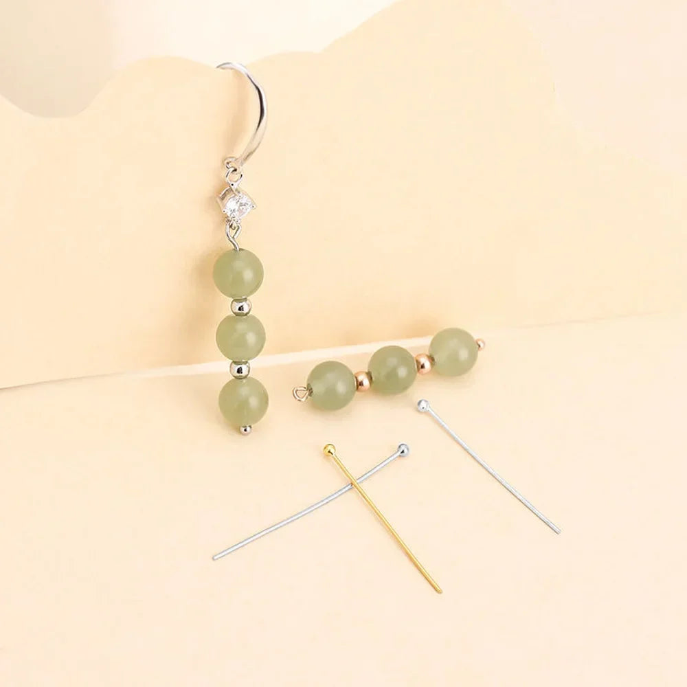 A stainless steel ball head pin with a silver hook and three light green beads.