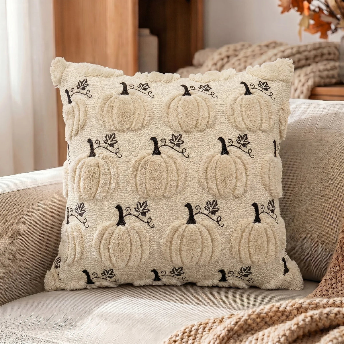 A beige fuzzy throw pillow cover featuring a repeating pattern of black pumpkin vines and leaves.