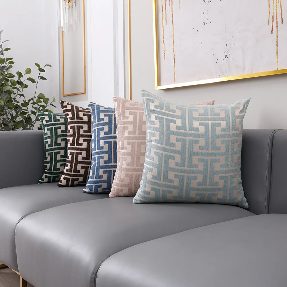 A collection of geometric jacquard lumbar pillows in shades of blue, gray, and beige displayed on a modern sofa.