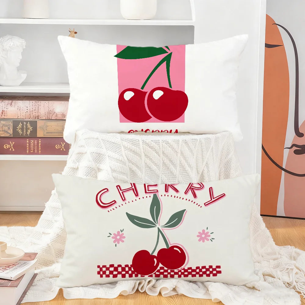 A white cushion cover featuring a graphic design of red cherries and green leaves.