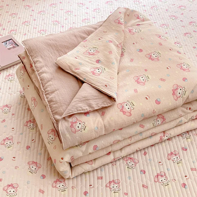 A stack of light pink cartoon quilting comforters with small pink animal designs resting on a quilted surface.